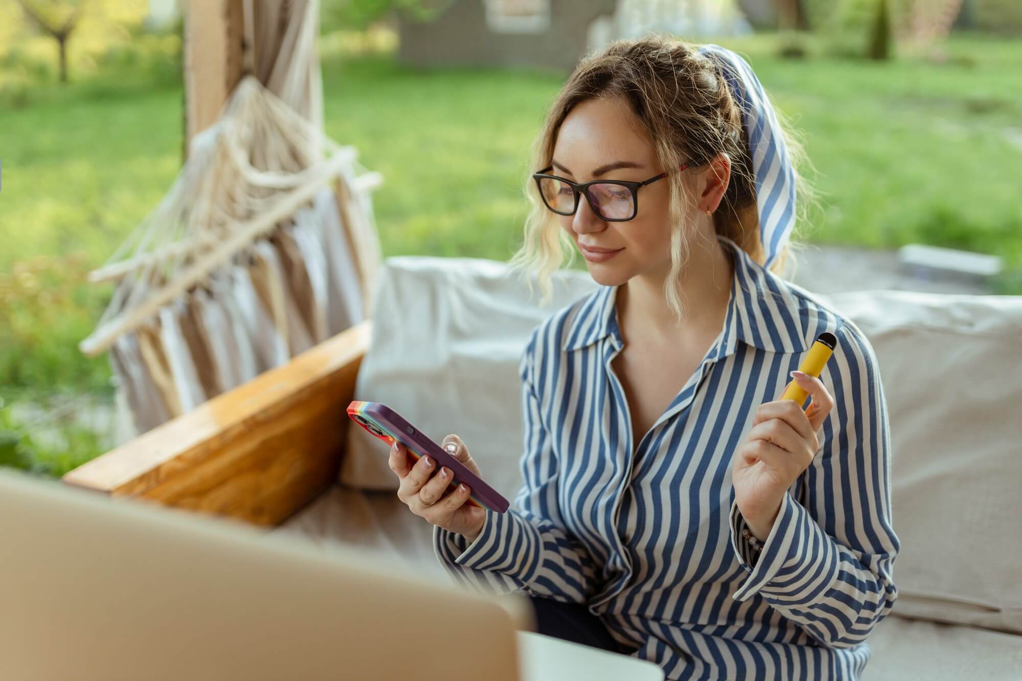A beautiful girl smokes an electrode cigarette and uses a smartphone. Event Organizer